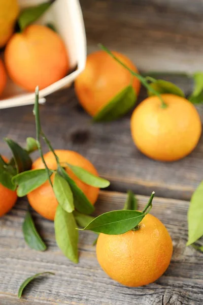 Verse, smakelijke mandarijnen met bladeren op houten tafel — Stockfoto