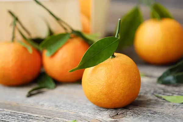Mandarini gustosi freschi con foglie sul tavolo di legno — Foto Stock