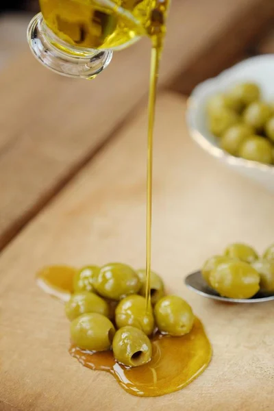 Delicious green olives and oil on the table