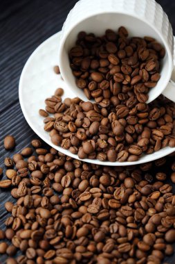 Kavrulmuş kahve çekirdekleri masada beyaz kupa  