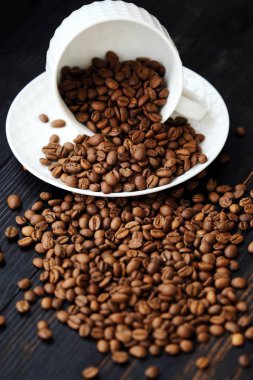 Kavrulmuş kahve çekirdekleri masada beyaz kupa  