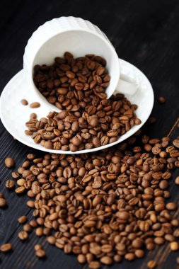 Kavrulmuş kahve çekirdekleri masada beyaz kupa  