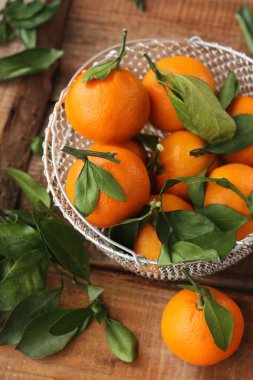 Masada yaprakları olan taze, sulu mandalinalar