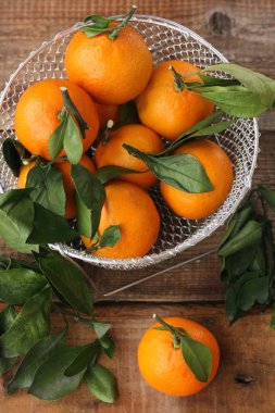 Masada yaprakları olan taze, sulu mandalinalar