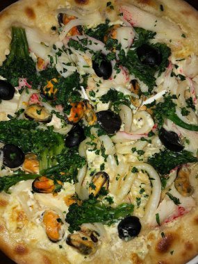 Deniz ürünleri peynirli ve brokoli soslu pizza.