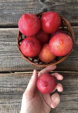 Tahta bir masada taze kırmızı erikler.