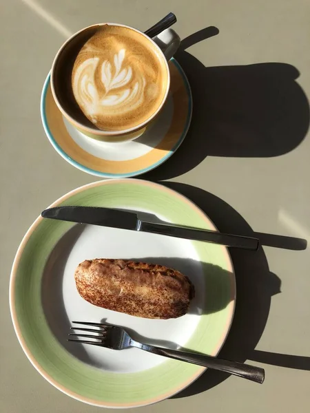 Fresh coffee and cocoa Eclair on the table