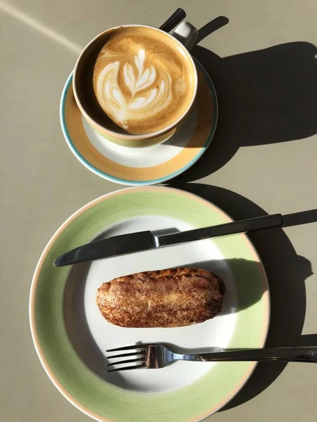 Fresh coffee and cocoa Eclair on the table