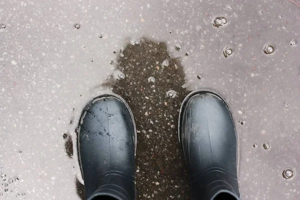 水たまりにゴム長靴の足 — ストック写真