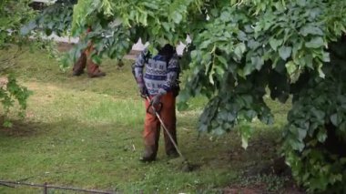 Bahçesinde çim biçme makinesi olan bahçıvan.