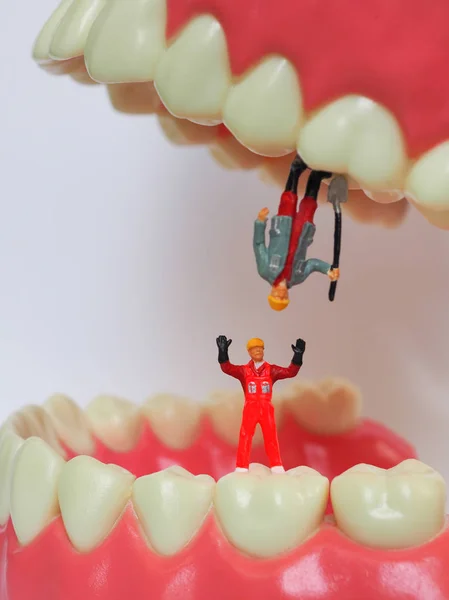 Miniature worker on plastic teeth of removable denture. Dental h — Stock Photo, Image