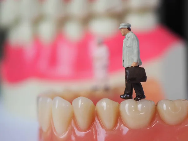 Miniature elderly man walking on plastic teeth of removable dent — Stock Photo, Image