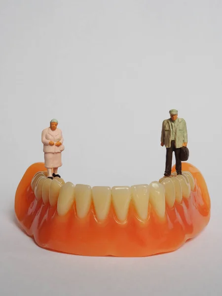 Casal idoso em miniatura em pé sobre dentadura removível, em branco — Fotografia de Stock