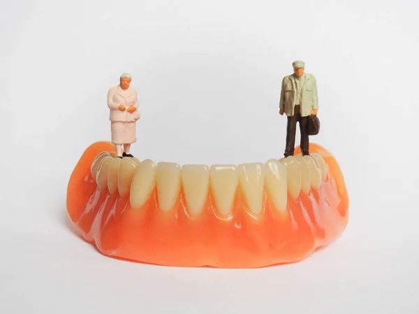 Miniature elderly couple standing on removable denture, on white — Stock Photo, Image
