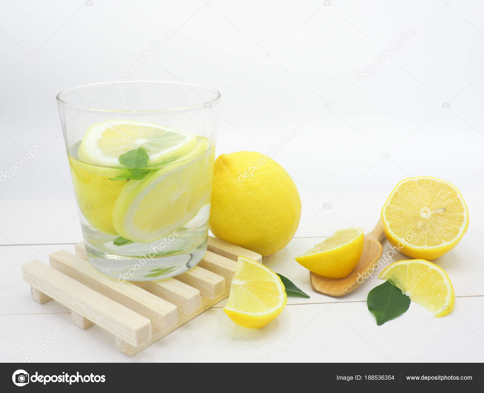 fresh lemon in water and lemon slice on white wood background