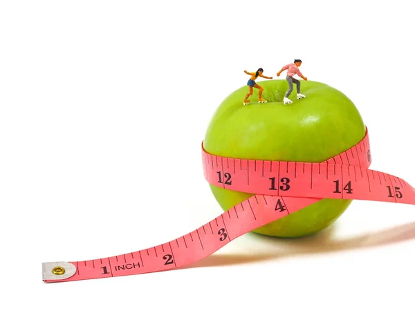 Patinaje miniatura de mujer sobre manzana verde y cinta métrica, delgada — Foto de Stock