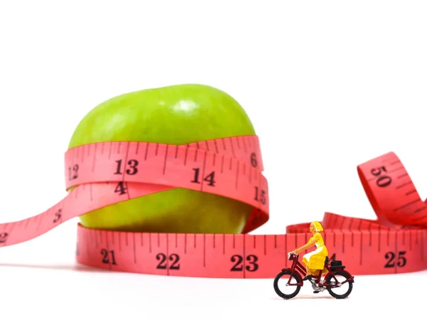 Miniatura mujer montar en bicicleta cerca de manzana verde y medir ta — Foto de Stock