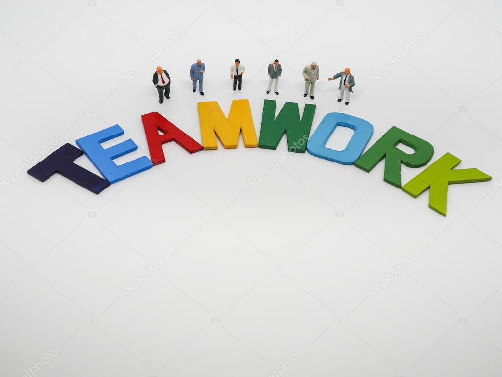 Miniature bussinessman with TEAMWORK word letters on white backg