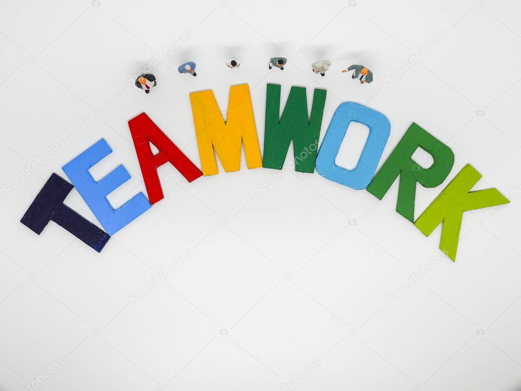 Miniature bussinessman with TEAMWORK word letters on white backg