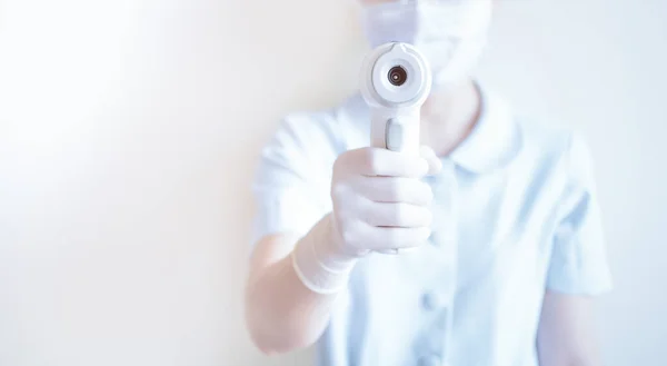 Pielęgniarka Nosząca Maskę Trzymająca Medyczny Termometr Czole Podczerwieni Celu Sprawdzenia — Zdjęcie stockowe
