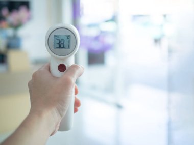 Vücut ısısını ölçmek için alın termometresi tutan kadın yüksek ateş gösteriyor. Coronavirüs salgınını önlemek için ilk tarama. Covid-19 ve Coronavirus konsepti.