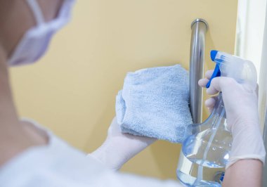 Asyalı kadınlar, covid-19 krizi sırasında koronavirüsün yayılmasını önlemek için evde alkol spreyi ya da antiseptik kullanarak çalışırlar. ev işi, ev işi ve sosyal uzaklık kavramı.