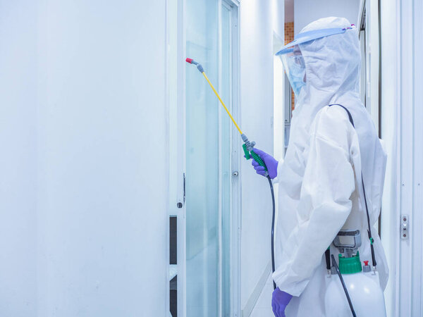 Азиатские женщины носят индивидуальные защитные костюмы или СИЗ, очки, маски и перчатки, делая дезинфекцию и дезинфекцию на общественной площади
