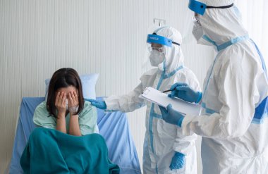 İki Asyalı doktor N95 maskeli ve yüz zırhlı PPE giyiyorlar.,