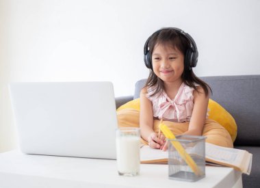 Sevimli Asyalı kız, ev karantinası sırasında online ders çalışmak için dizüstü bilgisayar kullanıyor. Çevrimiçi eğitim, evde eğitim, evde eğitim, sosyal uzaklık, kendini izole etme, koronavirüs, covid-19 konsepti.