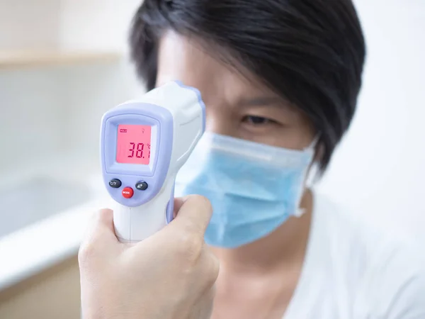 Kvinnlig Läkare Som Håller Medicinsk Infraröd Panna Termometer Kontrollerar Kroppstemperaturen Stockfoto