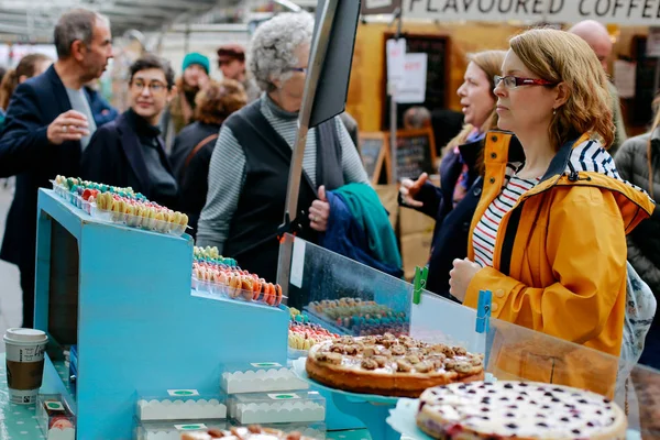 Woman looking at desserts sold on a market stall — Stock Photo, Image