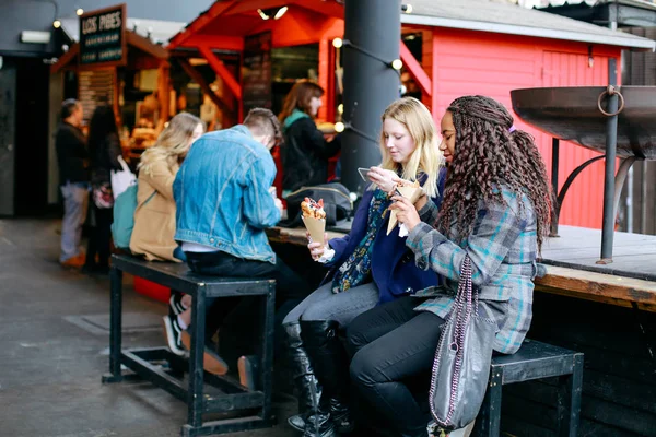 Jovens mulheres comendo e tirando uma foto da sobremesa na mão — Fotografia de Stock