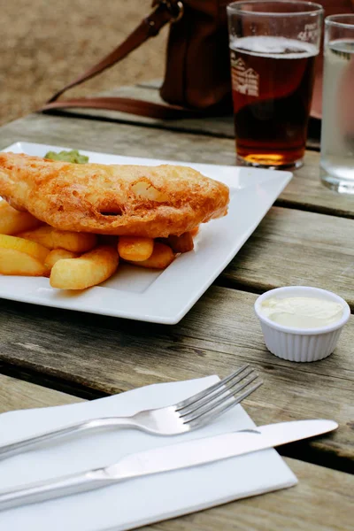 Peixe e batatas fritas em um pub ao ar livre mesa de madeira — Fotografia de Stock