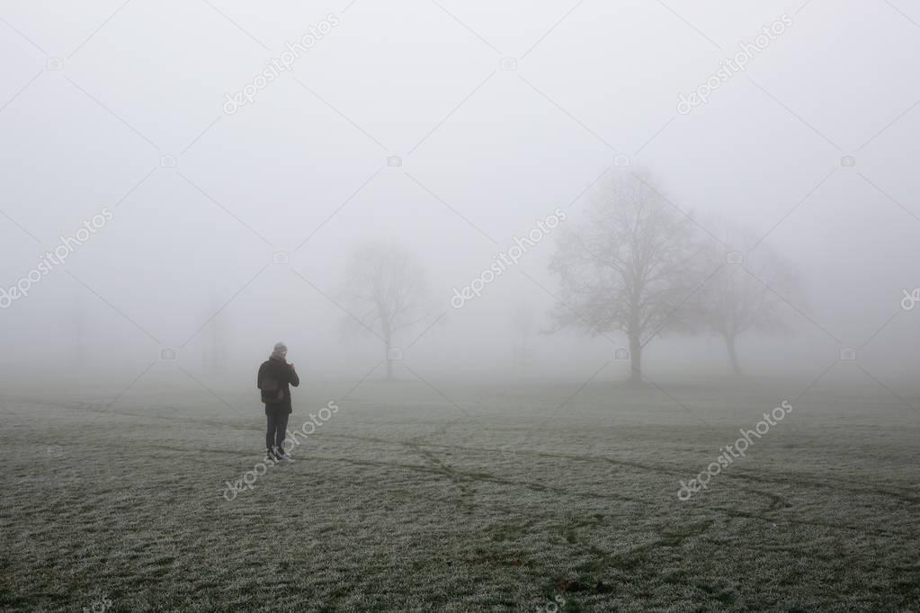 Man taking mobile photo of a park in fog