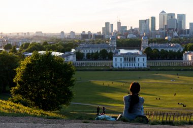 Londra manzarası üzerinde gün batımını izlemek yerde oturan kadın