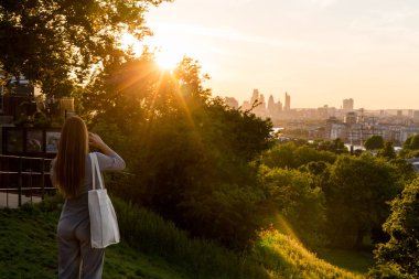 Günbatımı ve smartphone cep telefonu ile fotoğraf çekimi sırasında Greenwich Park, Londra, tepenin üstünde duran kadın