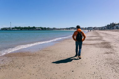 Bir kumsalda yürüyen genç adam