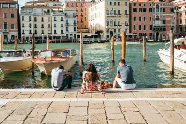 Tourists relax on the steps of Grand Canal, Venice. clipart