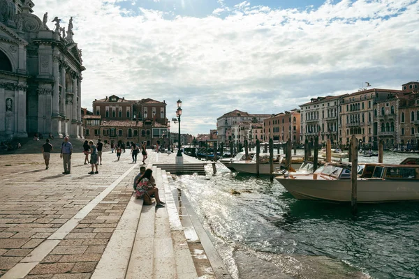 游客坐在京杭大运河，威尼斯，附近大教堂的台阶上圣玛丽亚 della 致敬. — 图库照片