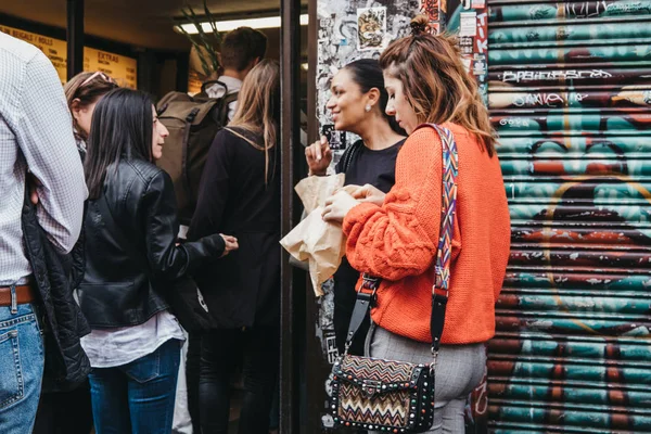 Pessoas comendo e fazendo fila para comprar bagels de uma famosa Beigel Shop em Brick Lane, Londres, Reino Unido — Fotografia de Stock