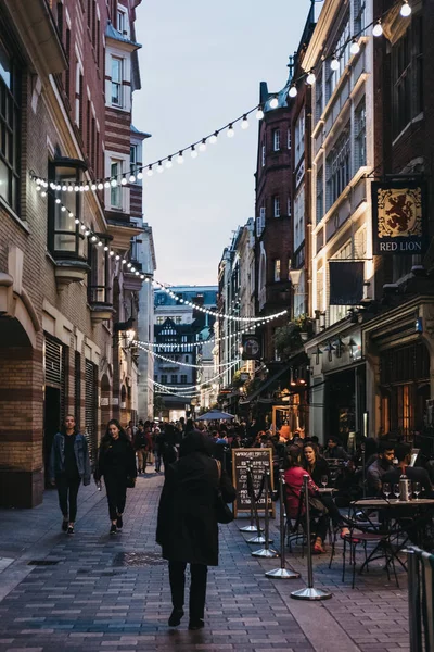 王ストリート、ロンドン、英国の光の文字列の下を歩く人々 — ストック写真