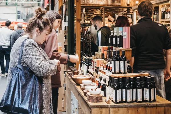 Vrouwen proberen olijfolie en azijn op een marktkraam in Borough Market, Londen — Stockfoto