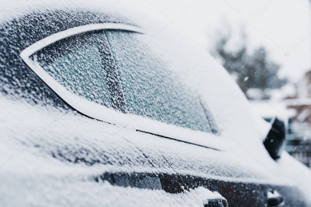 Black car covered in snow, ice on the windows, selective focus