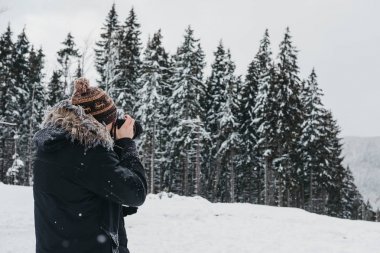 Kış ceket, şapka ve atkı alarak fotoğraf Dslr fotoğraf makinesi ile giyinmiş genç adam