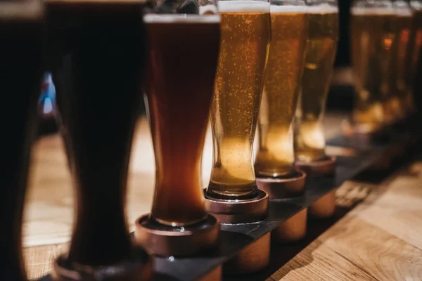 Close Rack Diferentes Tipos Cervejas Escuro Luz Uma Mesa Foco — Fotografia de Stock