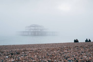Brighton, İngiltere - 17 Ekim 2017: West Pier Brighton, İngiltere'de en popüler sahil Hedef Yurtdışı turistler için bakarak sahilde oturan insanlar.