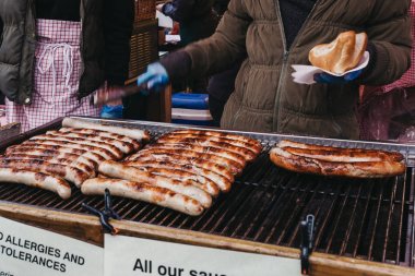 London, İngiltere - 10 Nisan 2016: Sosisli sandviç Borough Market, Londra'nın en büyük ve en eski gıda piyasaları pişirme bir piyasa ahır, tüccar.