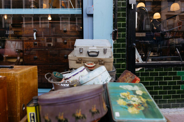 LONDON, UK - MARCH 21, 2016: Stack of vintage suitcases and various vintage items in Chatsworth Road Market. The market has a long heritage and is located on one of London's longest high streets.