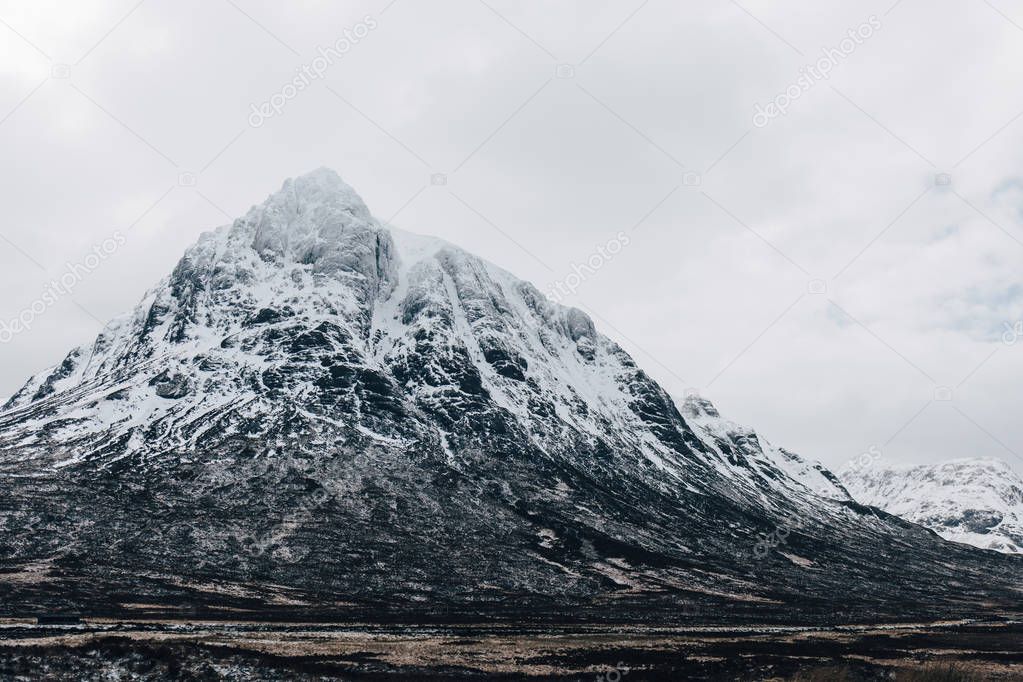 Snowcapped mountains in Scottish Highlands near Glencoe, Scotland, on a foggy spring day.