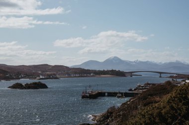 View of Skye Bridge and a small coastal village on Isle of Skye, Scotland, on a sunny day. View from Kyle of Lochalsh. clipart